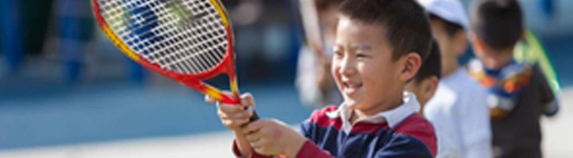 An Asian boy holding a tennis racket